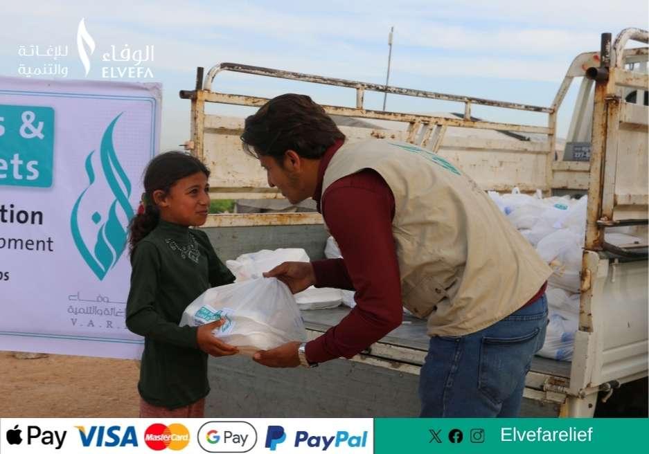 متطوّع من جمعية الوفاء يسلّم سلة غذائية لطفل